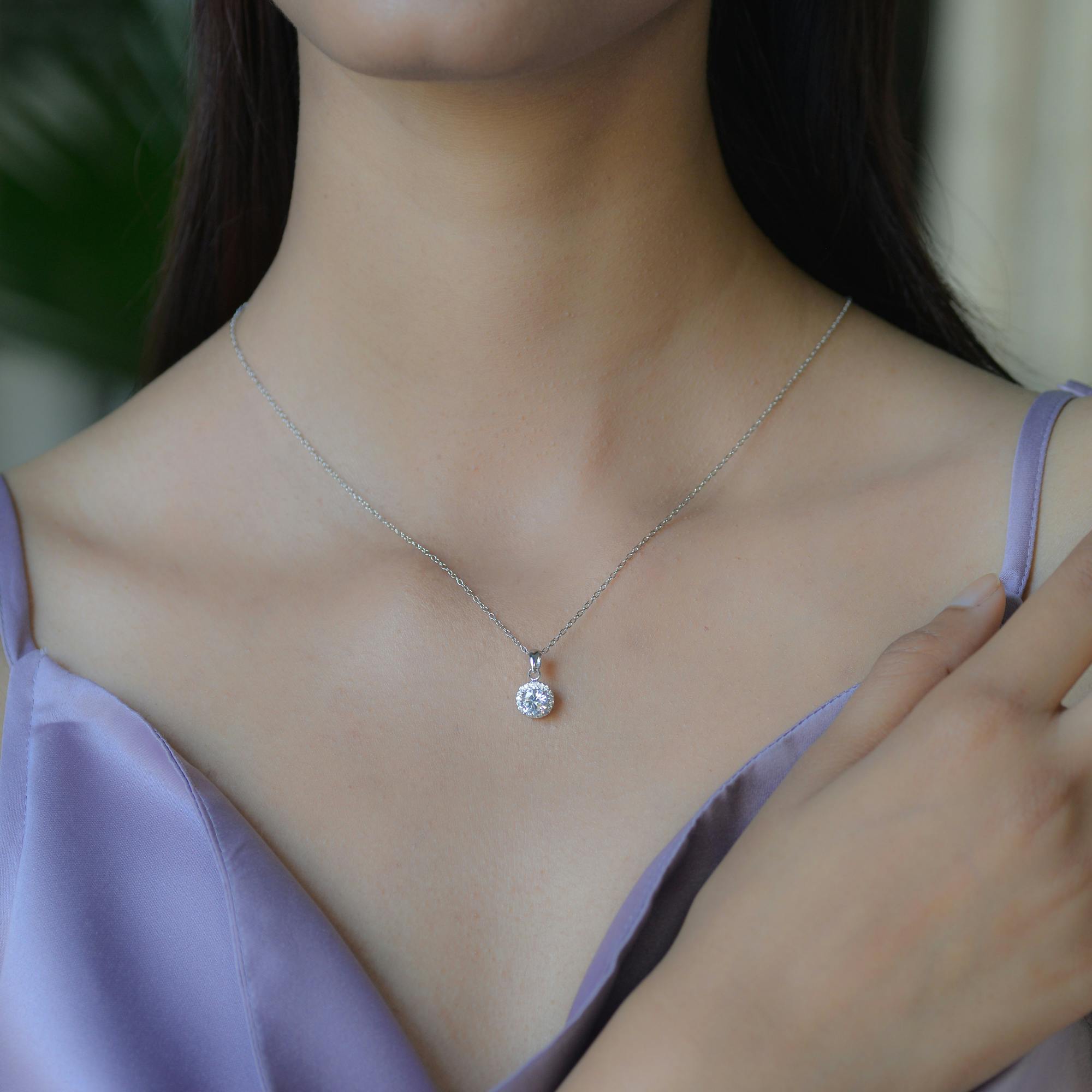 a cropped image of a woman wearing a white sapphire pendant